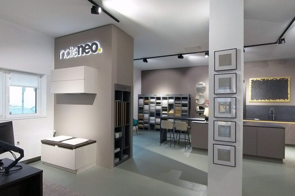 nolte neo Bereich in der Ausstellung von Neo mit Musterwand und Materialregal, im Hintergrund eine Musterküche mit Theke