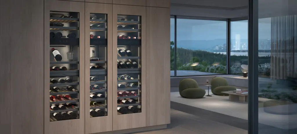 Drei nebeneinander eingebaute Gaggenau Weinklimaschränke mit Glastüren in einer Holzwand, dahinter Wohnbereich mit Seeblick
